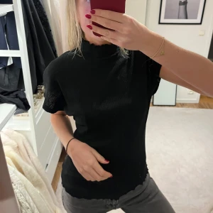 Svart ribbad polotopp - Snygg svart ribbad polotopp med korta ärmar. 