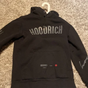 Svart hoodie från Hoodrich - Snygg svart hoodie från Hoodrich med tryck både fram och bak. Den har en justerbar huva och en stor ficka framtill. Perfekt för en avslappnad stil.