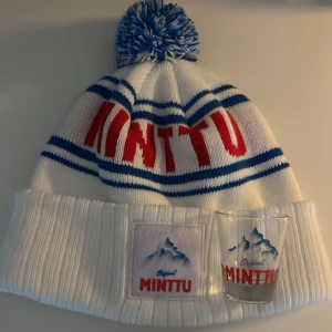 Vit mössa med Minttu-logga - Vit minttu mössa, perfekt för kalla dagar. Glas medföljer