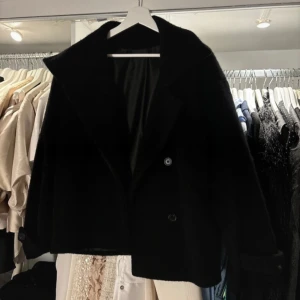 Svart kappa från arket  - Elegant svart kappa från arket med klassisk design och knappar framtill. Perfekt för kyligare dagar med sin stilrena look och bekväma passform. Använd 3 gånger så i nyskick, storlek 38! 