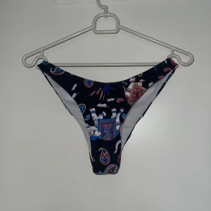 Mönstrad bikiniunderdel - Snygg bikiniunderdel med unikt mönster i olika färger på en mörk bas. Perfekt för en dag på stranden eller vid poolen.