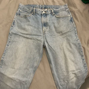 Blå jeans från Weekday - Säljer ett par blå jeans från Weekday i modellen Galaxy Loose Straight. De har en klassisk femficksdesign och är tillverkade i bomull. Perfekta för en avslappnad stil.