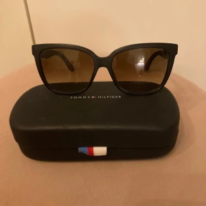 Svarta solglasögon från Tommy Hilfiger - Snygga svarta solglasögon från Tommy Hilfiger. De har mörka linser och kommer med ett stilrent fodral med märkets logotyp.  Nypris 2100 kr  ev frakt betalas av köpare