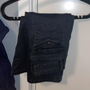 Svarta bootcut jeans från 157 - Snygga svarta bootcut jeans från 157 med klassisk femficksdesign och knappdetaljer. Perfekta för en stilren look.