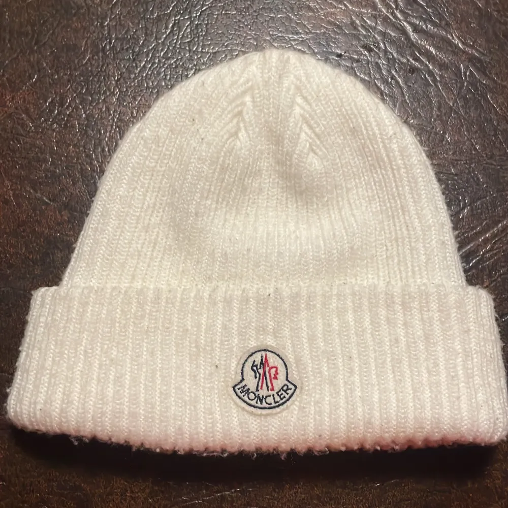 Snygg vit stickad mössa från Moncler med broderad logotyp framtill. Perfekt för kalla dagar med sin ribbade design som ger extra värme och stil.. Accessoarer.