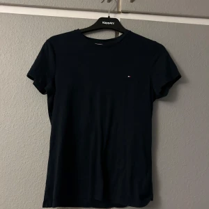 Svart t-shirt från Tommy Hilfiger - Säljer en stilren marinblå t-shirt från Tommy Hilfiger i storlek XS. Den är kortärmad och har en liten logga på bröstet. Perfekt för vardagsbruk eller att ha under en jacka. Passar till det mesta och är superbekväm!