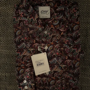 Helt ny Mönstrad skjorta från Oscar of Sweden - Snygg skjorta från Oscar of Sweden med ett färgglatt blommigt mönster. Skjortan har en normal passform och är långärmad med knappar framtill. Perfekt för att liva upp garderoben!