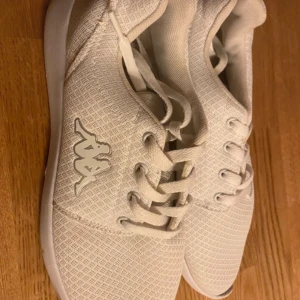 Vita sneakers från Kappa st42 - Snygga vita sneakers från Kappa med klassisk snörning och logotyp på sidan. Skorna har en stilren design med mönstrad sula för bra grepp. Perfekta för en avslappnad stil. Knappt använda