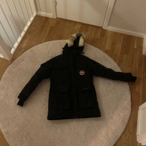 Svart parkajacka från Canada Goose - Säljer en svart parkajacka från Canada Goose med pälsdetaljer på huvan. Den är använd flera gånger och har några små hål som knappt märks. Om du vill ha bild på hålen är det bara att fråga! Priset är förhandlingsbart.