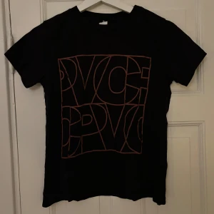 Svart t-shirt - Snygg svart t-shirt från Visual Clothing Project med ett stort grafiskt tryck i brunt på framsidan. Perfekt för en casual look.