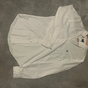 Vit skjorta från Ralph Lauren - Säljer en klassisk vit skjorta från Ralph Lauren i storlek S. Skjortan har en broderad logotyp på bröstet och knappar framtill. Perfekt för en stilren look. Slim fit 