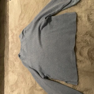 En blå stickad tröja - Säljer denna blåa stickad tröjan med utsvängda armar på, har använt få tal gånger. Slutet av tröjan är den ribbad o två öppningar, fin design! Den är lite nopprig men de syns knappt! Denna är för stor för mig därför säljs den💞Frakten står på köparen!
