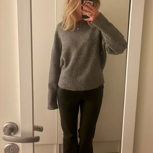 Grå stickad tröja - Mysig grå stickad tröja med långa ärmar och ribbstickade muddar. Perfekt för kyligare dagar och enkel att matcha med olika outfits.