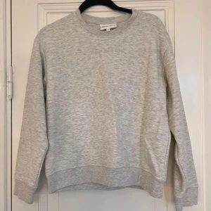 Grå sweatshirt från Röhnisch - Säljer en stilren och bekväm grå sweatshirt från Röhnisch i storlek XS. Tröjan har en klassisk rund halsringning och långa ärmar. Perfekt för en avslappnad look eller träning. Den är i mycket bra skick och redo för nya äventyr!