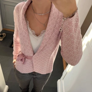 Rosa stickad kofta  - Rosa mönstrad kofta med snörning från Happy Holly i storlek 36/38. Fint skick. Använd gärna köp nu!