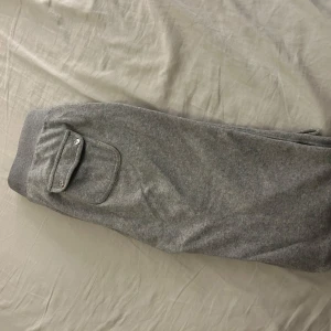 Grå mjukisbyxor från Juicy Couture - Säljer ett par supermysiga grå mjukisbyxor från Juicy Couture i storlek XS. Dem är inte använda mycket, men dem två metall bitarna som ska sitta på snörena har gått av, anars inga synliga defekter🩶
