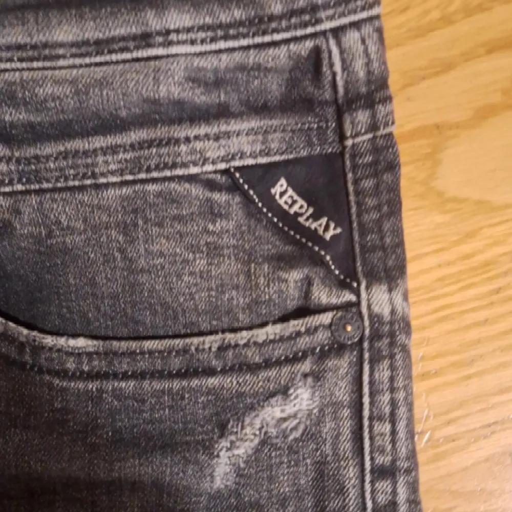 Säljer ett par grå Replay jeans i bra skick. De har en snygg sliten look med detaljerade slitningar vid fickorna. Perfekta för en casual stil och passar till de flesta tillfällen. Märket Replay syns tydligt på fickan och bak i midjan.. Jeans & Byxor.