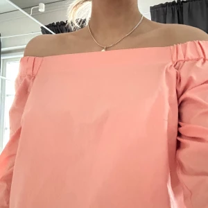 Rosa offshoulder topp - Snygg rosa offshoulder topp med långa ärmar. Perfekt för en somrig look. Enkel och stilren design som passar till många olika outfits.