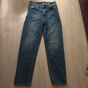 Blå jeans från Replay - Snygga blå jeans från Replay med klassisk femficksdesign och knappgylf. Perfekta för en avslappnad stil. De har en rak passform och är tillverkade i slitstarkt denim. Storlek: W/29,30 L/30,31