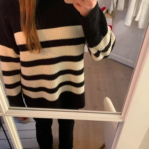 Svart och vit randig stickad tröja - Säljer en mysig svart och vit randig stickad tröja med långa ärmar. Perfekt för kyliga dagar och ger en stilren look. Passar bra till jeans eller leggings. Knappt använd! Storlek 158/164