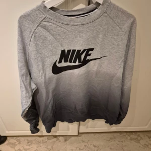 Grå sweatshirt från Nike - Säljer en grå sweatshirt från Nike med svart logga på bröstet. Tröjan har långa ärmar och en bekväm passform, perfekt för vardagsbruk.