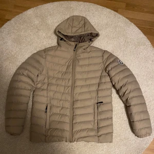 Beige Vinterjacka Polo Club - S - Snygg beige dunjacka från Vinson Polo Club med huva och dragkedja. Jackan har ett quiltat mönster och en logotyp på ärmen. Perfekt för kyliga dagar. Använt bara 3 gånger och köpt på stadium för 1049 men säljer den för mindre eftersom den passar inte