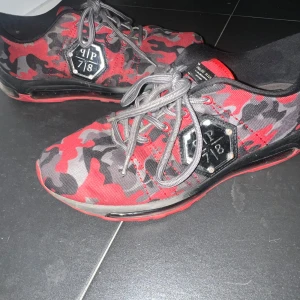 Röda camo sneakers från Philipp Plein  - Snygga och unika sneakers från Philipp Plein i rött och svart kamouflagemönster. Skorna har grå snörning och en cool metallplatta LIMITED EDITION, Äkta!