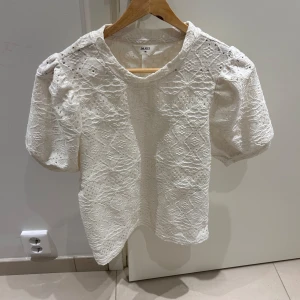 Vit spetsblus från Object - Säljer en söt vit spetsblus från Object i storlek XS. Blusen har korta puffärmar och ett vackert spetsmönster som ger en romantisk känsla. Perfekt för vår och sommar! 🌸