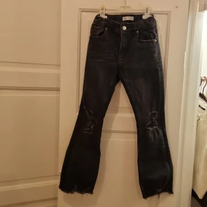 Svarta jeans från Zara - Säljer ett par coola svarta jeans från Zara i storlek 140. De har en snygg slitning på knäna och fransiga benslut för en trendig look.