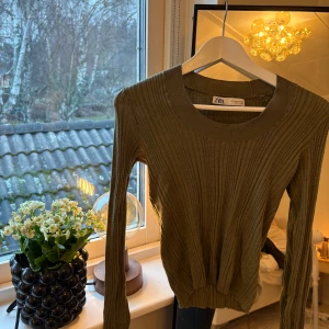Olivgrön ribbad tröja från Zara - Säljer en snygg olivgrön ribbad tröja från Zara. Den är i mycket bra skick och har en skön passform med långa ärmar. Otroligt skönt material!