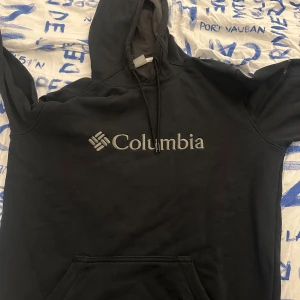 Svart hoodie från Columbia - Säljer en svart hoodie från Columbia i bra skick. Den har en klassisk passform med en stor ficka fram och justerbar huva. Perfekt för kyliga dagar eller som en bekväm vardagströja. 🖤