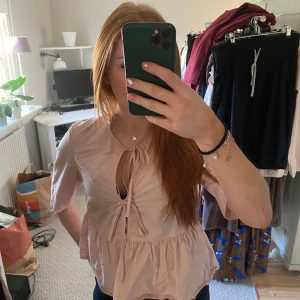 Ljusrosa blus med knytning - Säljer en söt ljusrosa blus med knytning framtill. Blusen har trekvartsärmar och en luftig passform, perfekt för vår och sommar. Den är gjord i ett lätt och bekvämt material, vilket gör den idealisk för både vardag och festliga tillfällen.