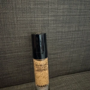 Foundation från Chanel - Säljer en lyxig foundation från Chanel, Les Beiges. Den har en elegant design med svart lock och genomskinlig flaska som visar de små pigmentkulorna. Perfekt för en naturlig och strålande look. Passar alla hudtyper och ger en jämn täckning. Shade:B10