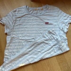 Vit och ljusblå randig t-shirt från Levi's - Säljer en snygg vit och ljusblå randig t-shirt från Levi's i storlek L. Jag tycker den är liten i storleken! 💙 använd några få gånger men i bra skick!