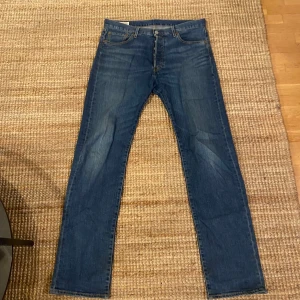 Levis 501 jeans i blå denim - Säljer ett par klassiska Levis 501 jeans i blå denim. De har en straight passform och är i mycket bra skick. Perfekta för både vardag och fest! De har knappgylf och fem fickor. Passar till alla säsonger och är ett måste i garderoben. 