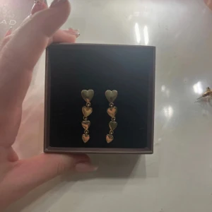 Guldörhängen med hjärtan - Säljer ett par superfina guldörhängen med tre små hjärtan i rad. Köparen betalar frakten, tar helst emot swich💕