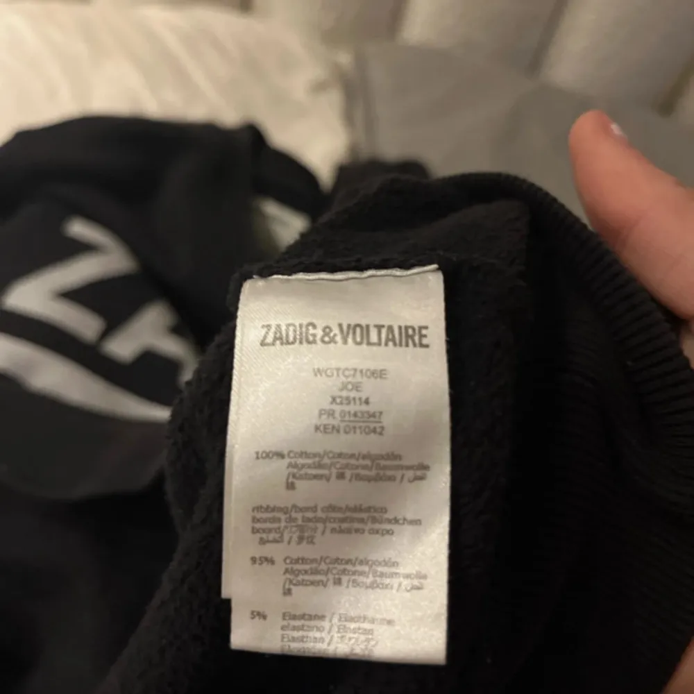 Säljer en svart tröja från Zadig & Voltaire med texten 'ZADIG ROCKS' i vitt på framsidan. Tröjan är i bomull och elastan, vilket gör den både bekväm och stretchig. Perfekt för en sommarkväll eller en avslappnad dag ute. Passar bra till jeans eller kjol!. Tröjor & Koftor.