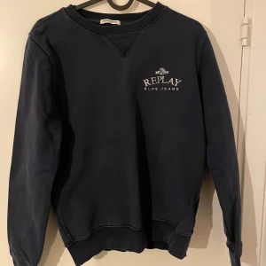 Mörkblå sweatshirt från Replay - Säljer en snygg mörkblå sweatshirt från Replay i ekologisk bomull. Tröjan har en klassisk rund hals och långa ärmar, perfekt för både höst och vinter. Den är i bra skick och har en stilren logga på bröstet. Perfekt för en casual look!