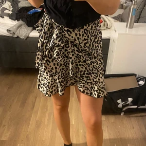 Leopardmönstrad kjol med volang - Säljer en superfin leopardmönstrad kortkjol med volangdetaljer. Perfekt för en utekväll eller fest! Kjolen har en omlott-design som ger en snygg passform. Materialet känns lätt och bekvämt, vilket gör den idealisk för sommarens varma dagar. 🐆✨