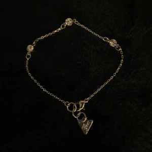 Armband från GUESS - Snyggt silverarmband från GUESS med 3 stenar längs kedjan och ett triangulärt hänge vid låset med GUESS loggan och en liten diamant på. Oanvänt. Pris kan diskuteras vid snabb affär. 💕