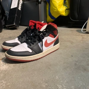 Nike Air Jordans i svart, vitt och rött - Säljer ett par Nike Air Jordans i klassisk färgkombination av svart, vitt och rött. Skorna har en snygg design med snörning och är i mycket bra skick. Perfekta för både vardag och fest!
