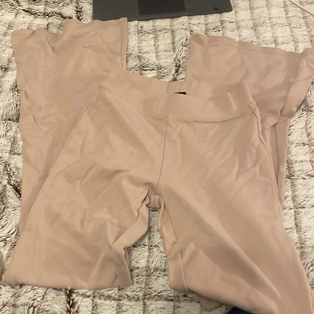 Säljer ett par snygga beige byxor från Gina Tricot i storlek XXS. De är i ett mjukt och bekvämt material, perfekt för en avslappnad stil. Byxorna har en enkel design utan mönster eller detaljer, vilket gör dem lätta att matcha med olika toppar. Perfekta för både vardag och mysiga hemmakvällar!. Jeans & Byxor.