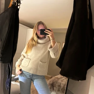 Beige stickad polotröja - Mysig beige stickad polotröja med stora fickor fram. Perfekt för hösten och vintern. Tröjan har långa ärmar och en bred polokrage. Den kommer tyvärr inte till användning längre och är i ett väldigt bra skick💗