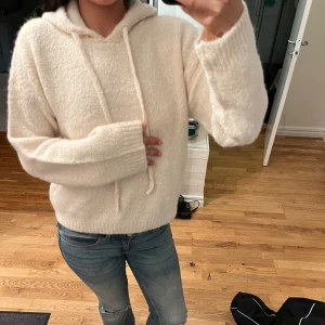 Beige hoodie i mjukt material - Säljer en jättefin vit/beige stickat hoodie från Gina. Den har en luva och två snören som man kan justera om man vill. Den är i storlek Xs och passar mig som brukar ha S/M. Prislappen e kvar. 