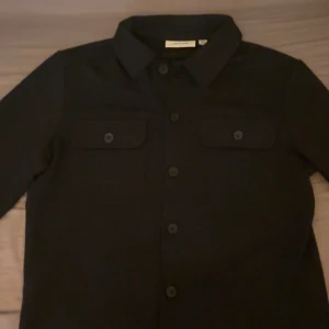 Mörkblå overshirt - Säljer en stilren mörkblå overshirt från Only & Sons i storlek XS. Perfekt för höst och vår med sina långa ärmar och knappar framtill. Om ni vill ha bättre bilder på den kom privat för det blir konstigt med plick appen när man lägger upp bilder. Och såklart om de finns frågor skriv också privat 😄Nypris runt 799