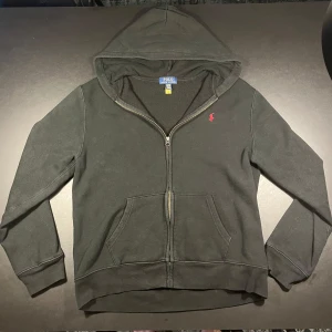Ralph Lauren Zip Hoodie - Ralph lauren zip hoodie i svart med röd logga. Skick 7/10 annvänd men inga hål eller fläckar. Storlek XL i barn storlek sitter ungefär som XS i vuxen storlek. Köpt från kidsbransstore nypris: 1195kr Hör av er vid frågor eller funderingar!