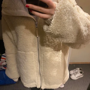 Beige teddyjacka med dragkedja - Mysig beige teddyjacka i mycket bra skick. Perfekt för höst och vinter med långärmad design och dragkedja framtill. Jackan har en avslappnad passform och är superbekväm att ha på sig. Perfekt för att hålla sig varm och stilren under kyliga dagar!