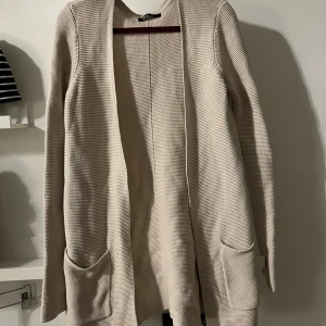 Beige stickad kofta från Gina Tricot - Säljer en beige stickad kofta från Gina Tricot i storlek XS. Koftan har en enkel och stilren design som passar till det mesta. 