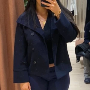 Mörkblå kappa - Säljer en stilren mörkblå kappa med knappar framtill. Den har en klassisk krage och långa ärmar, perfekt för höst och vår. Passar både till vardags och lite finare tillfällen. Jag har S/M i storlek men kappan passar mig fast den är 145/152. ❤️💞