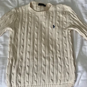 Beige stickad tröja från Ralph Lauren - Säljer en snygg beige/benfärgad stickad tröja från Ralph Lauren. Perfekt för höst och vinter, supermysig och passar till allt! ✨Inga särskilda märkbara defekter men är lite urtvättad och väl använd, därav priset💕💕nypris ca 2000kr